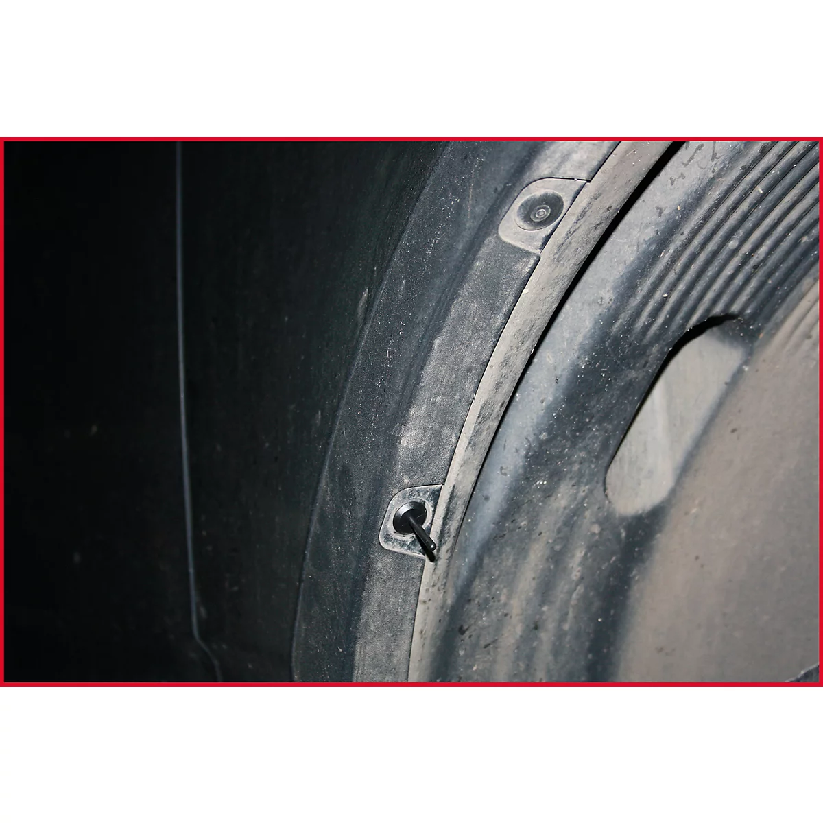 Nahaufnahme eines schwarzen Kotflügels mit Schrauben und schmutziger Innenfläche.